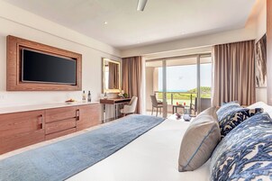 A modern hotel room with a large bed, a desk, a flat-screen TV, and a balcony with a view.
