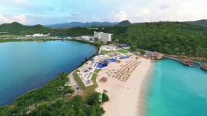 An aerial view of a resort with a beach, a pool area, and overwater bungalows. - Royalton Antigua, An Autograph Collection All-Inclusive Resort (St. John's)