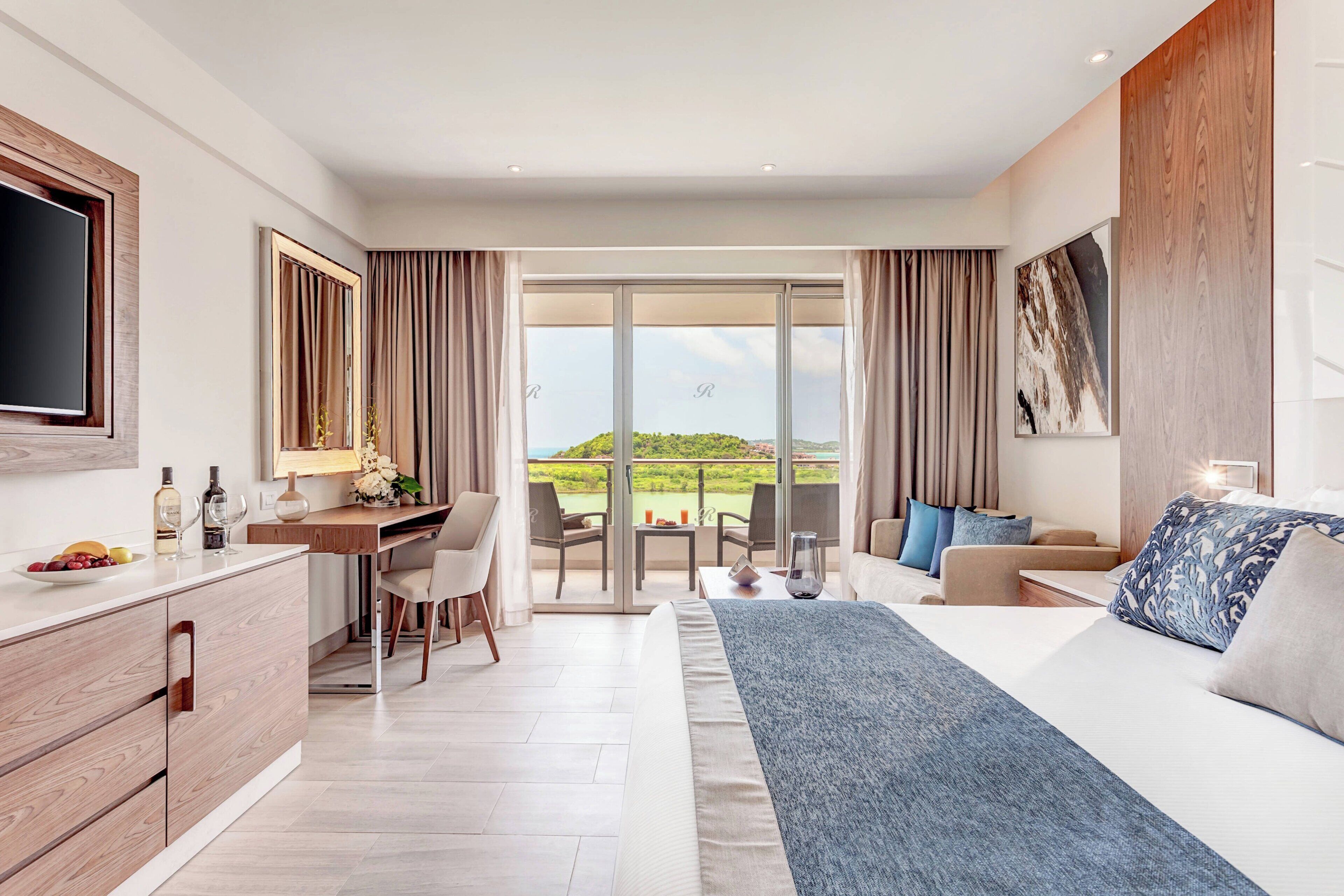 Ein modernes Hotelzimmer mit einem großen Bett, einem Schreibtisch und einem Balkon mit Blick auf die Landschaft.