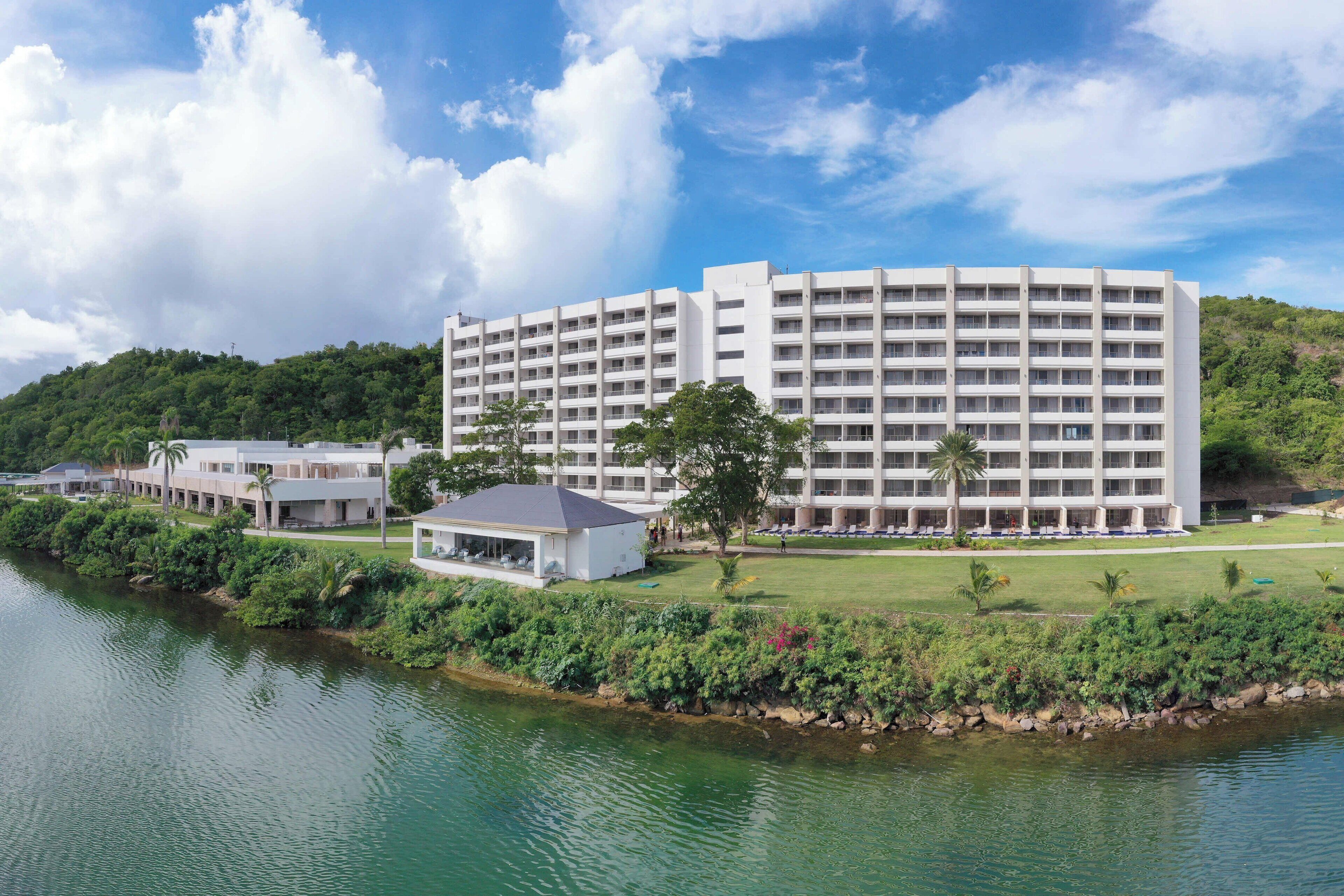 A large, multi-story hotel with a flat roof, located beside a body of water.