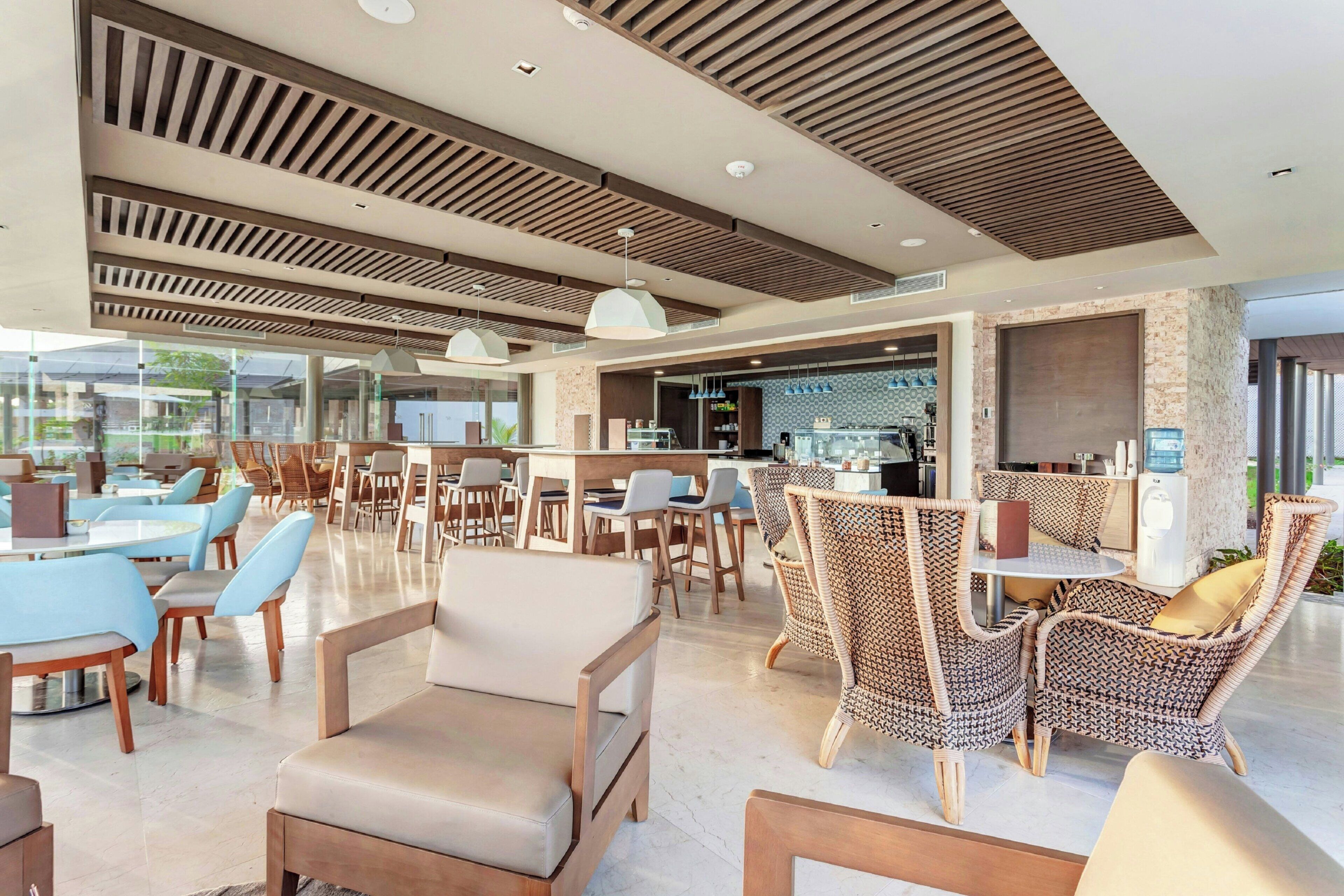 A modern hotel lobby with seating areas, a bar, and a view of the outdoors.