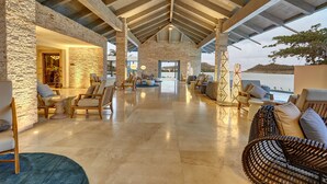 A spacious indoor area with a high ceiling, stone walls, and a view of the sea. - Royalton Antigua, An Autograph Collection All-Inclusive Resort (St. John's)