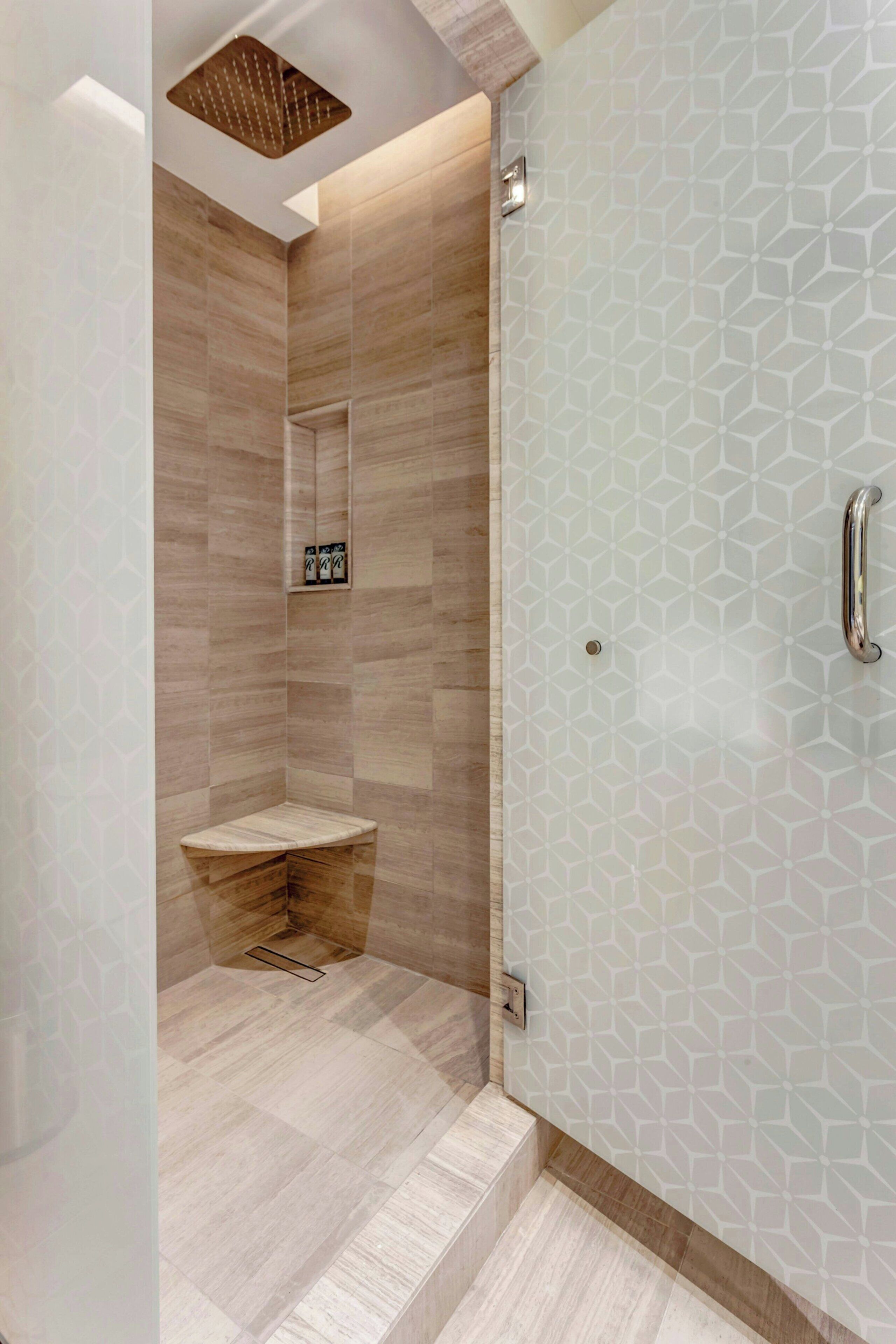 A modern bathroom with a shower, a vanity, and a geometric-patterned wall.