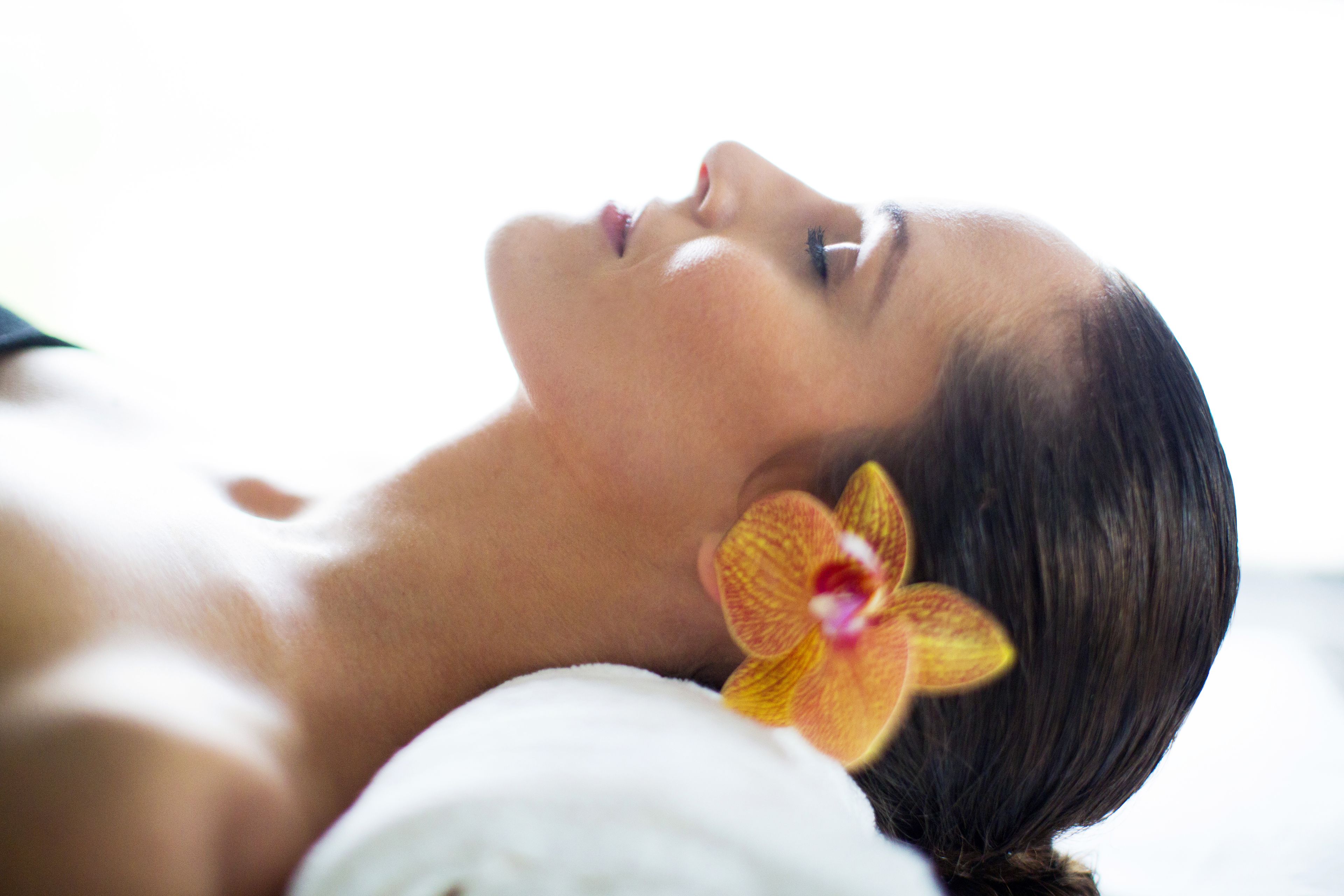 A person lying down with a flower accessory in their hair.