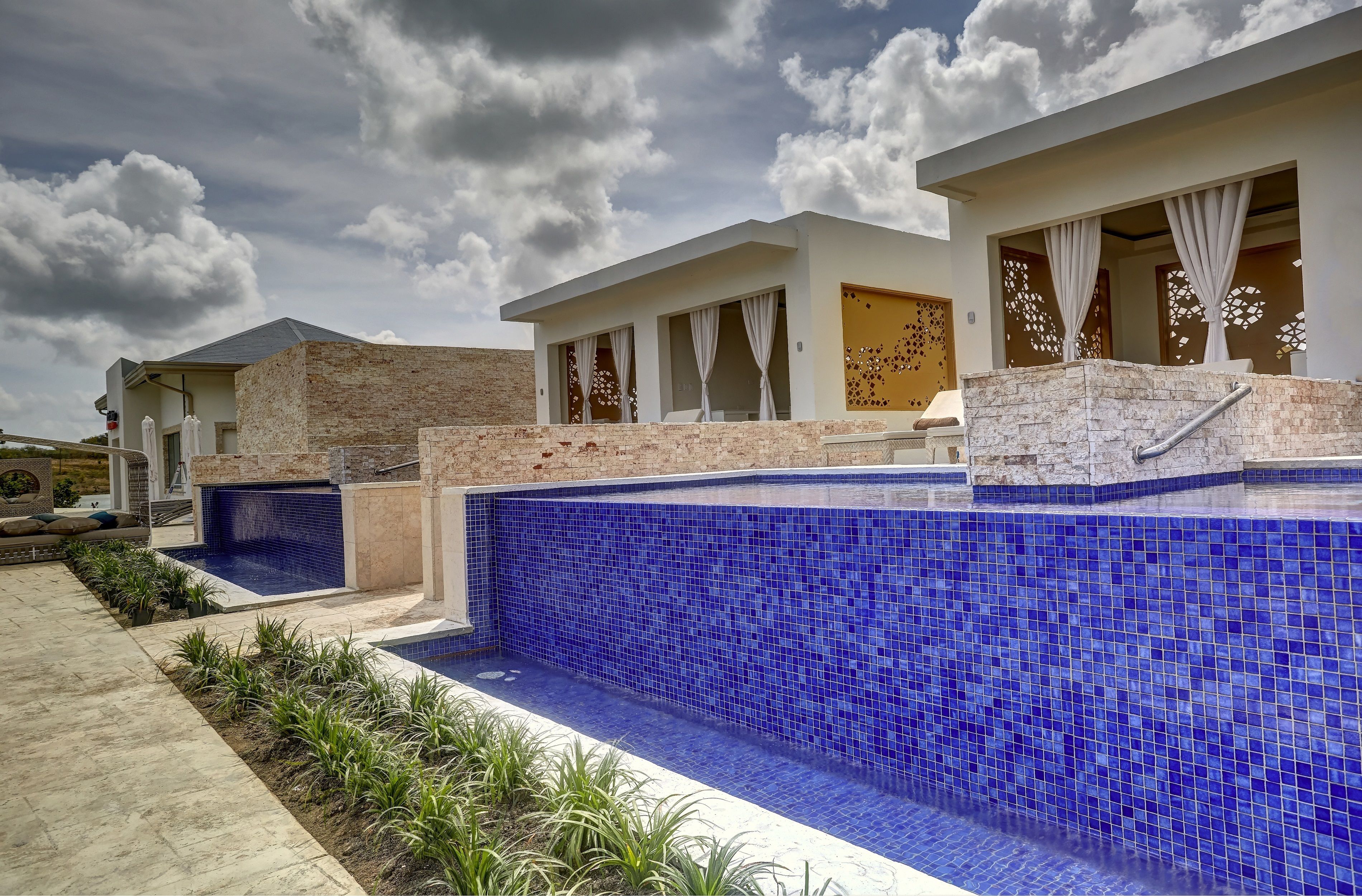 A modern building with a swimming pool, a covered patio, and a view of the sky.