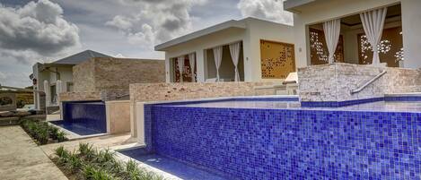 A modern building with a swimming pool, a covered patio, and a view of the sky.
