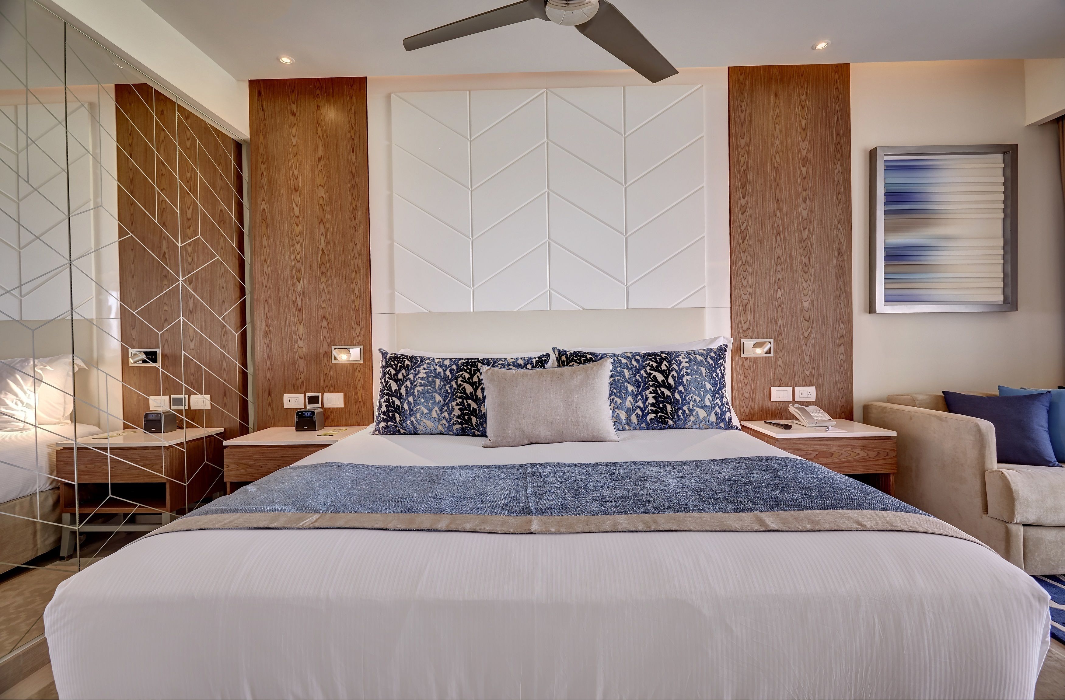 A modern hotel room with a large bed, a desk, and a chair.