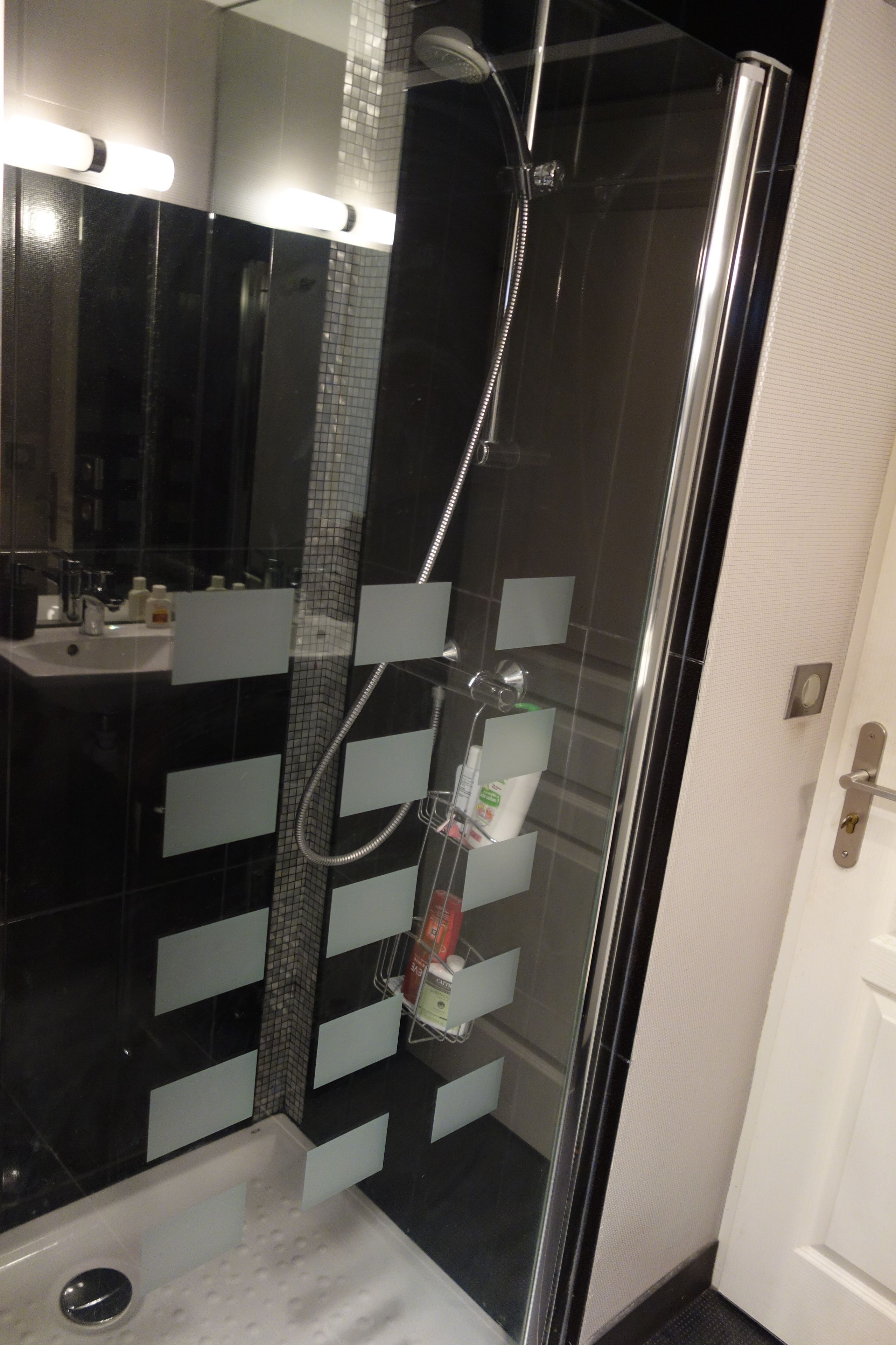 Un baño moderno con ducha acristalada, un lavabo blanco y un espejo.