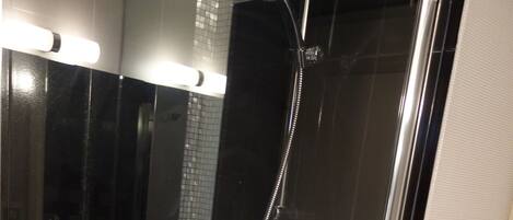 Un baño moderno con ducha acristalada, un lavabo blanco y un espejo.