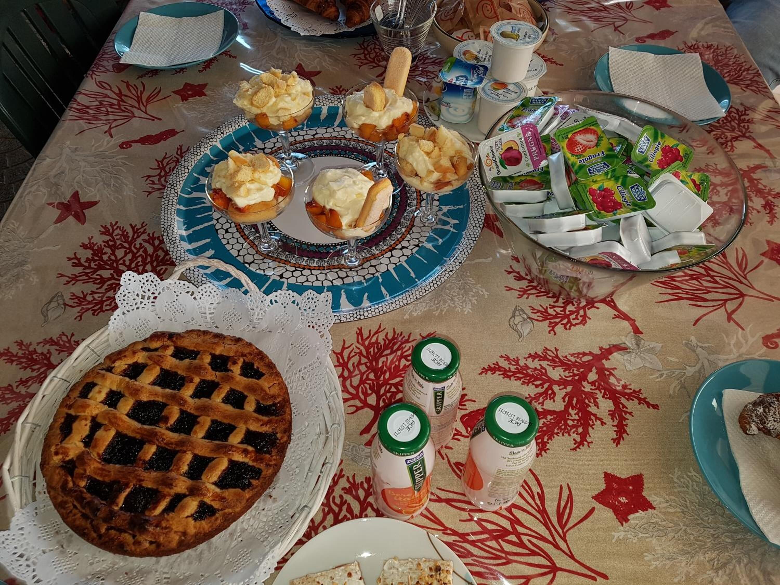 Una mesa dispuesta con tarta, vasitos de postre, yogures y salsas.