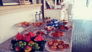 Ein reichhaltiges Buffet mit verschiedenen Speisen, darunter Obst, Gebäck und Getränke.