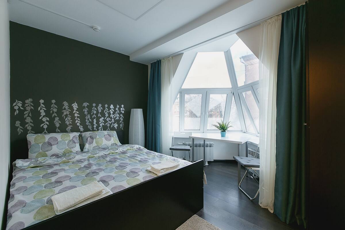 Ein Schlafzimmer mit Bett, Schreibtisch und Fenster.