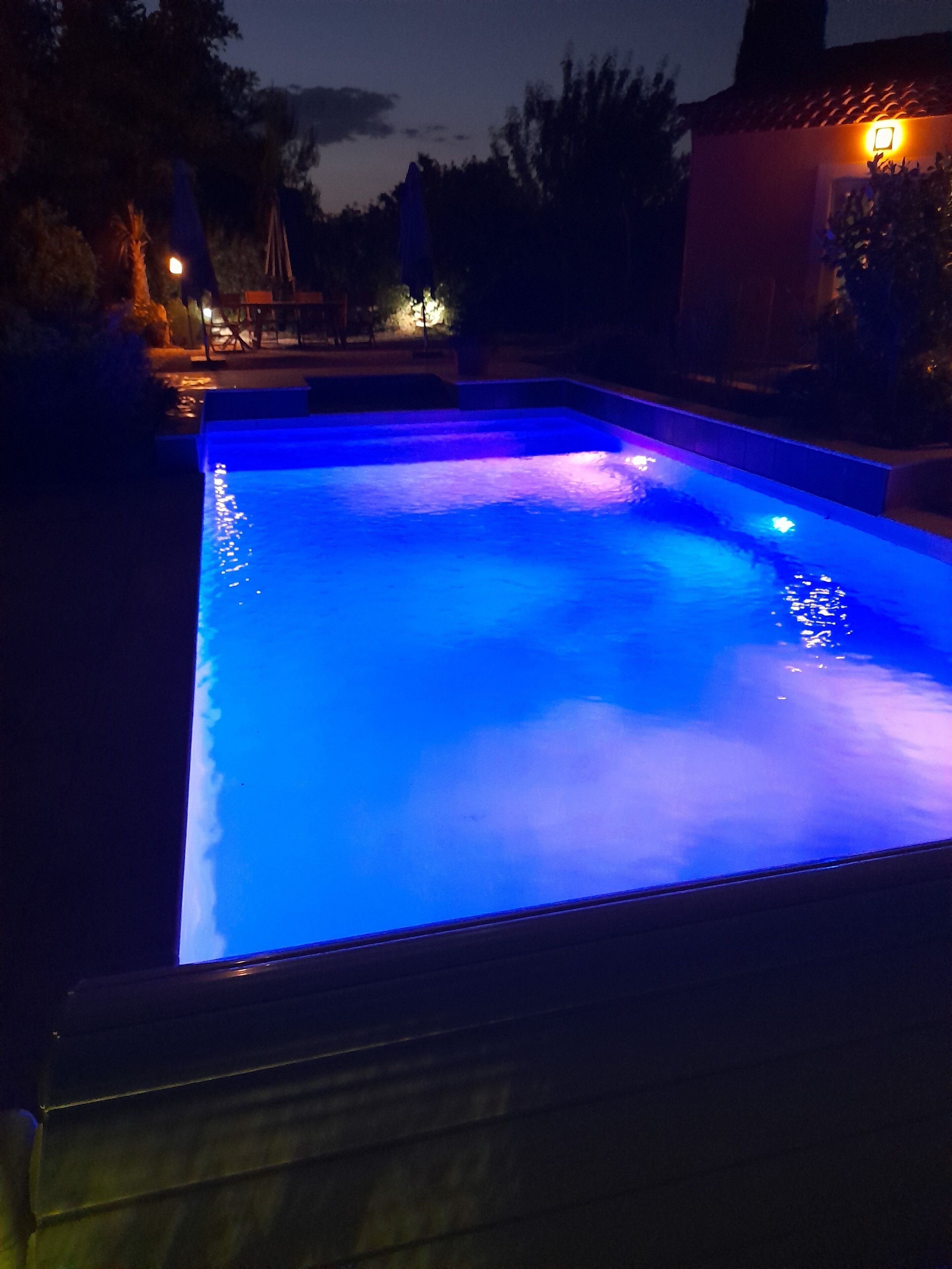 Een zwembad met blauwe verlichting in de nacht.