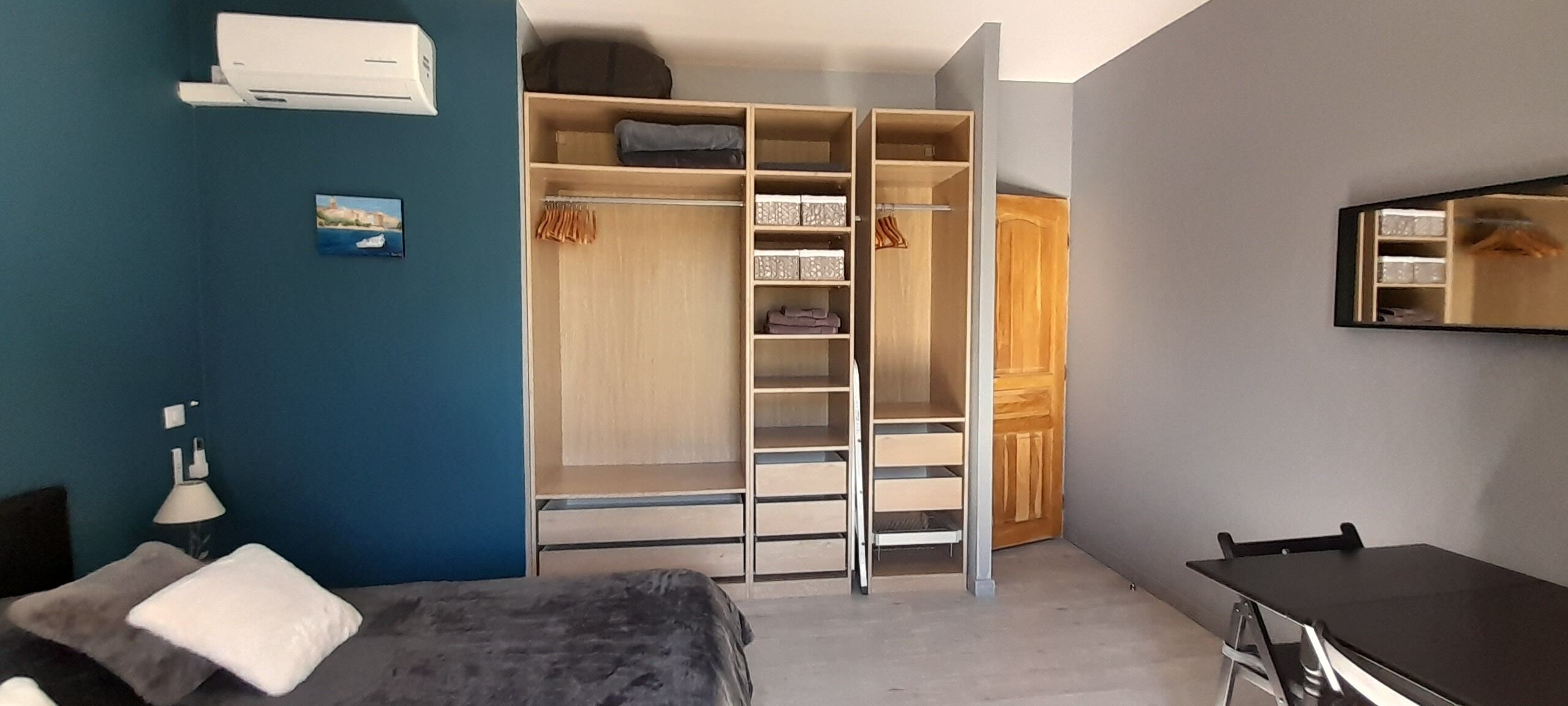Un dormitorio con cama, escritorio, armario y espejo.