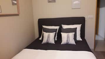 A neatly made bed with a black headboard and white bedding. There are two pillows with a feather design on them.