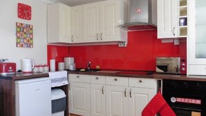 Et køkken med hvide skabe, rød backsplash, en mikroovn, en brødrister og en opvaskemaskine.