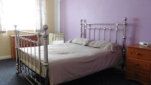 Une chambre à coucher avec un lit à ossature métallique, une table de chevet en bois et une commode.