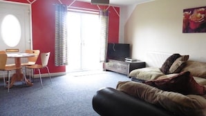 Une chambre avec un lit, une télévision, un bureau avec des chaises et une fenêtre avec des rideaux.