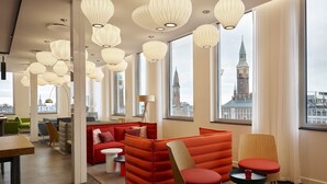 Ein modernes Interieur mit großen Fenstern, roter Sitzmöbeln und ungewöhnlichen Pendelleuchten.