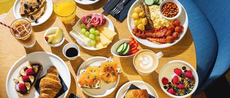 A breakfast buffet with various dishes, including toast, eggs, bacon, and pastries.