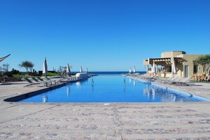 Una piscina al aire libre, sombrillas, sillones reclinables de piscina