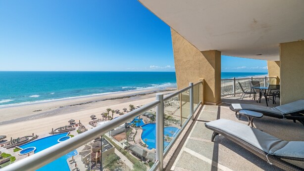 A balcony with a view of a beach and a pool area. - Encanto Living 1103 -3BR by Kivoya (Puerto Peñasco)