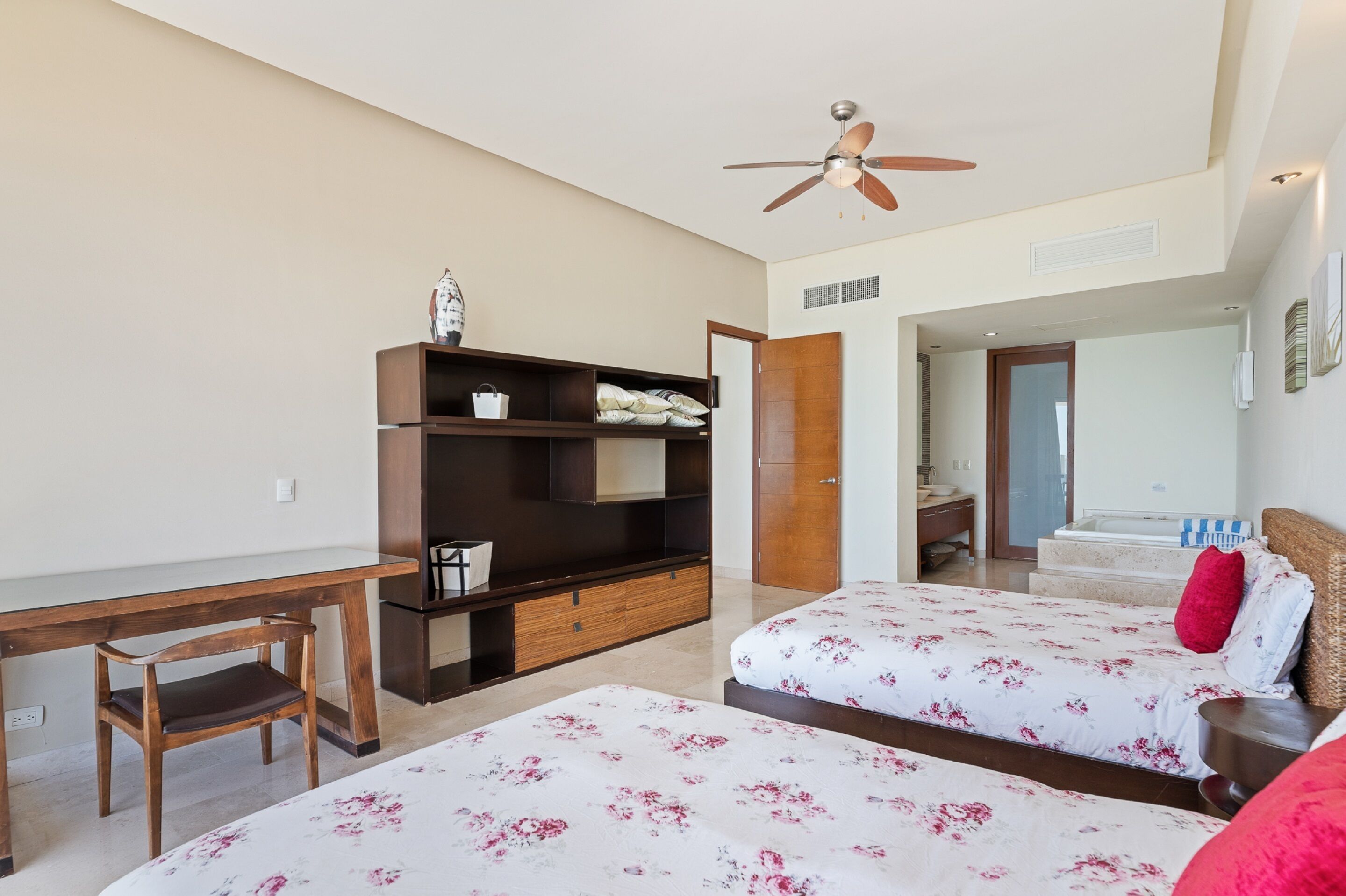 Ein Hotelzimmer mit Bett, Schreibtisch, Kleiderschrank und Deckenventilator.
