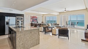 A spacious living area with a kitchen, a dining area, and a balcony with a view of the ocean. - Encanto Living 1103 -3BR by Kivoya (Puerto Peñasco)
