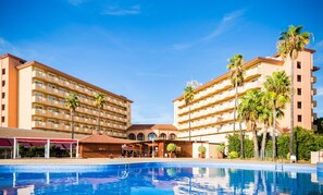 Un hotel con una gran piscina, varios pisos y palmeras.