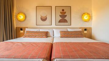 Una cama doble con almohadas estampadas, dos lámparas fijadas a la pared y una obra de arte abstracta en la pared.
