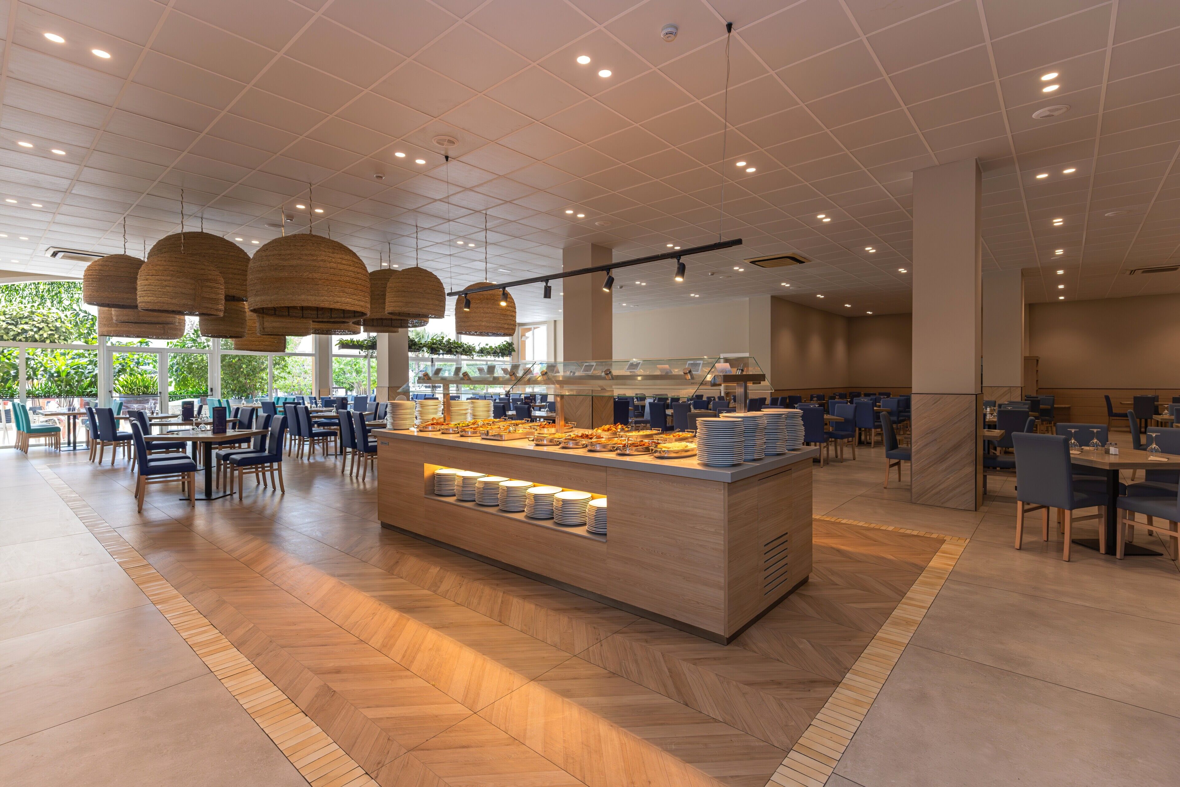 Un comedor moderno con mesas de buffet, diversas opciones de asientos e iluminación empotrada en el techo.