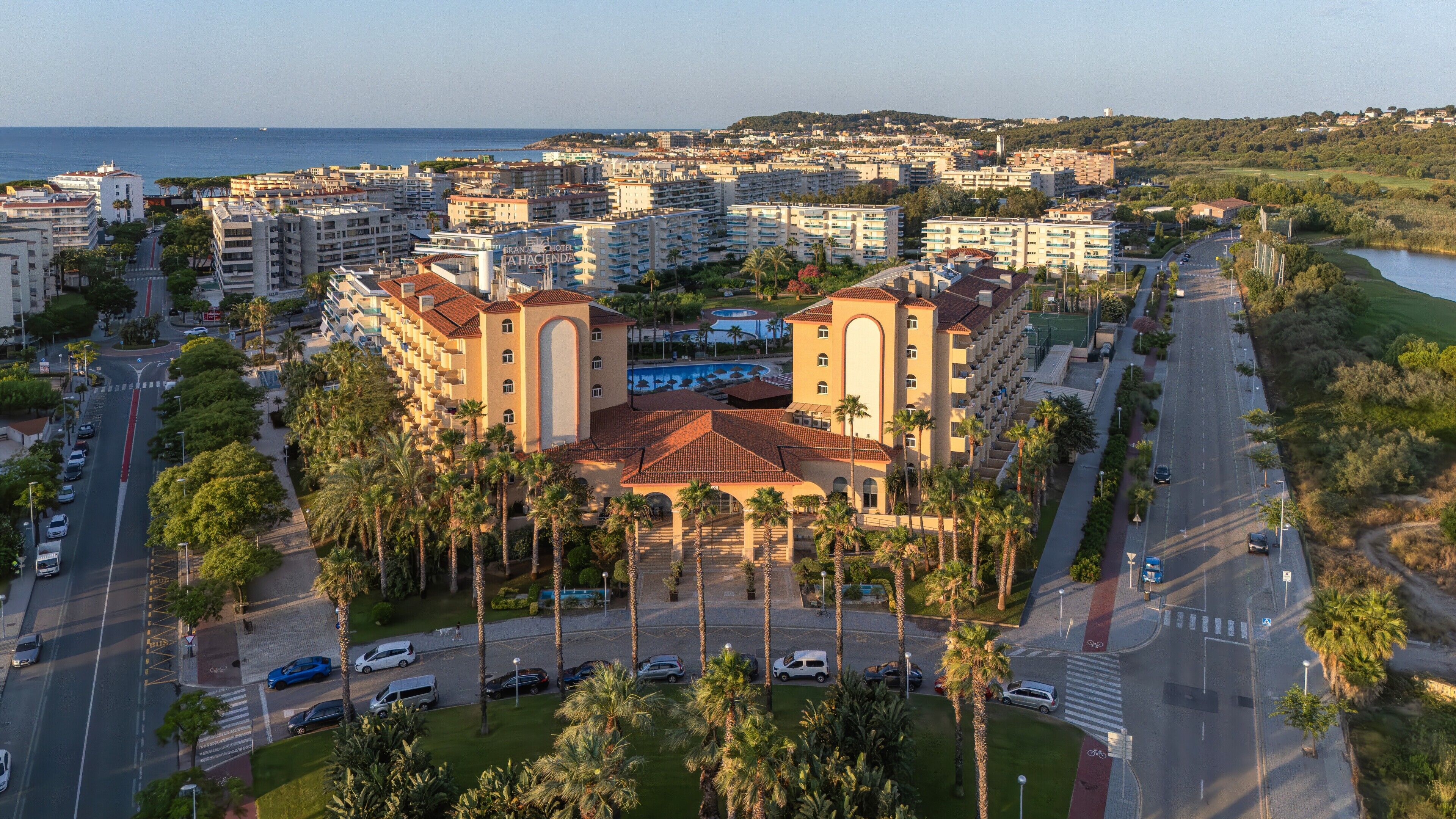 A hotel with multiple floors, a swimming pool, and a view of the sea.
