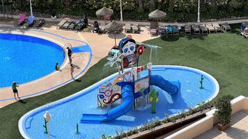 A water park with a large pool, slides, and lounge areas.