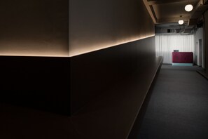 A modern hotel lobby with a curved wall, a reception desk, and a red seating area. - Avangarda Suites (Belgrade)