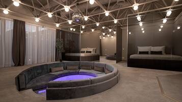 Una habitación moderna y luminosa con un área de estar circular, una cama y un espejo grande.