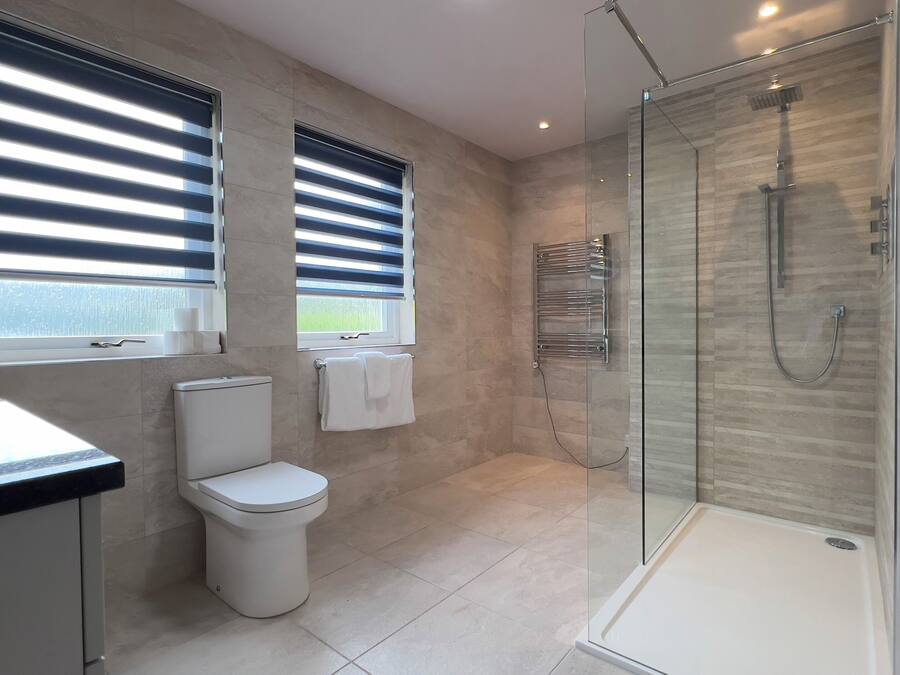 Un bagno moderno con doccia vetrata, un water e un lavabo con piano.