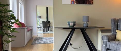 Een moderne woonkamer met een eethoek, een zwarte tafel met een schaal en een lamp, en een grijze bank.