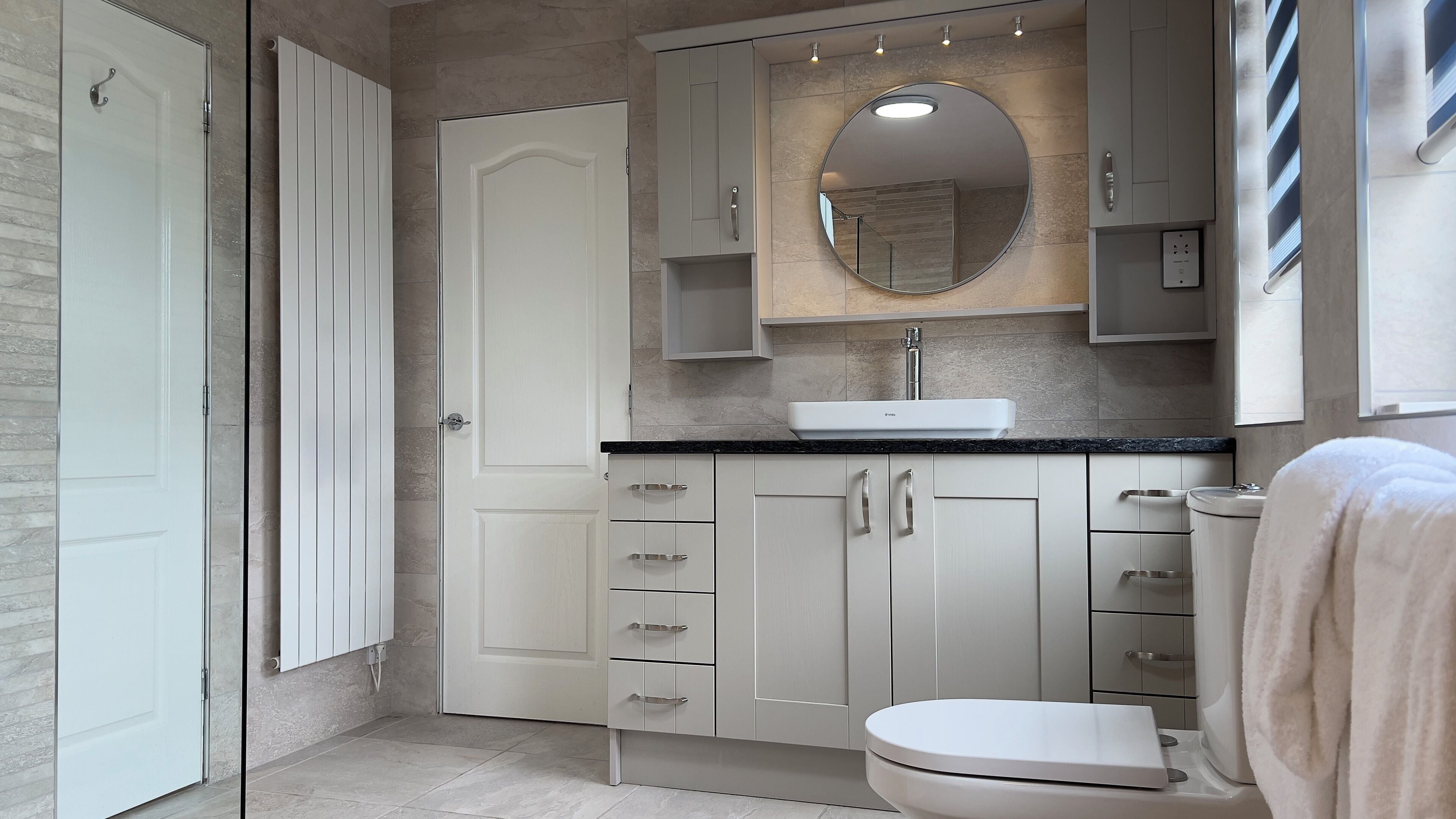 A modern bathroom with a white toilet, a sink with a mirror above it, and a shower area.