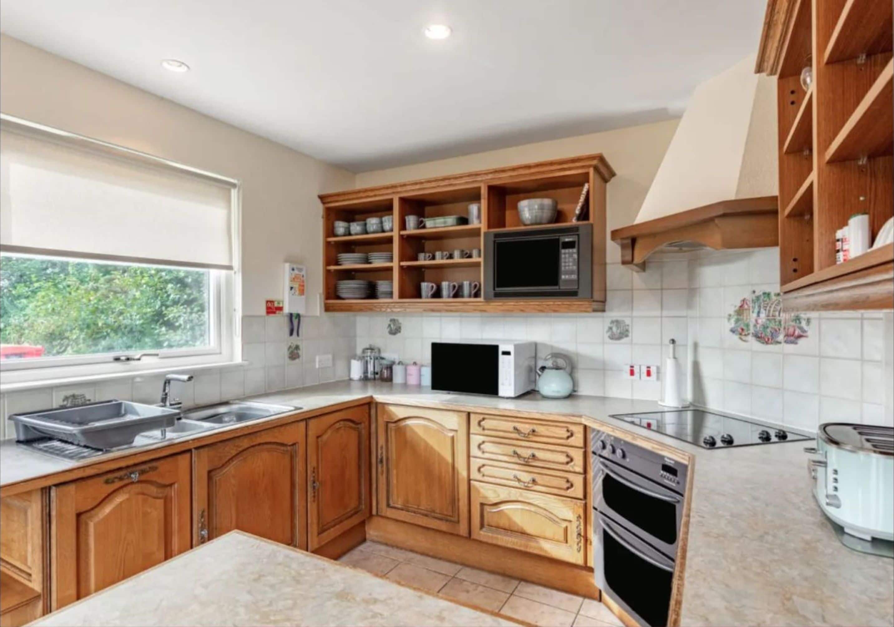 A kitchen with wooden cabinets, a microwave, a stove, and a sink.