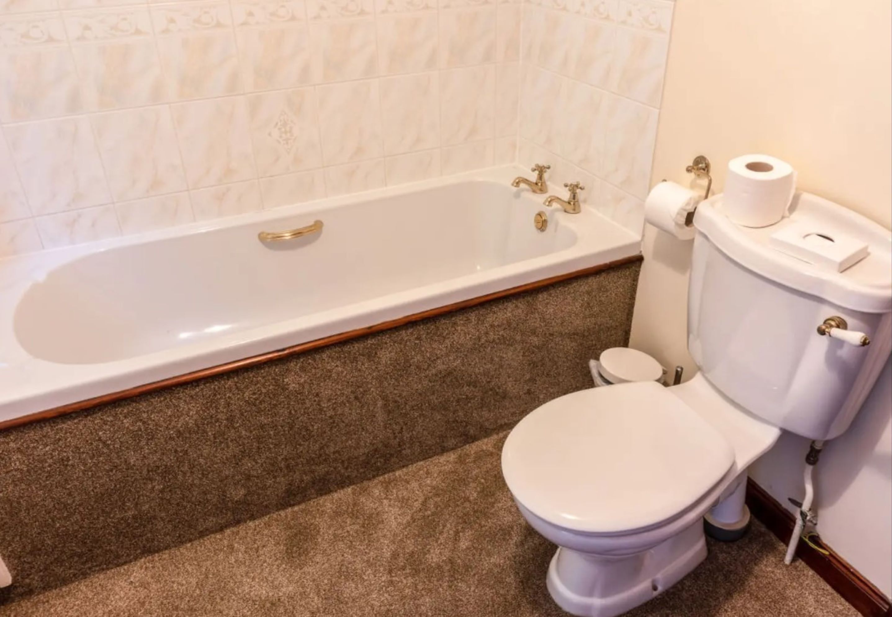 A bathroom with a white bathtub, a white toilet, and a toilet paper holder.