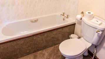 A bathroom with a white bathtub, a white toilet, and a toilet paper holder.