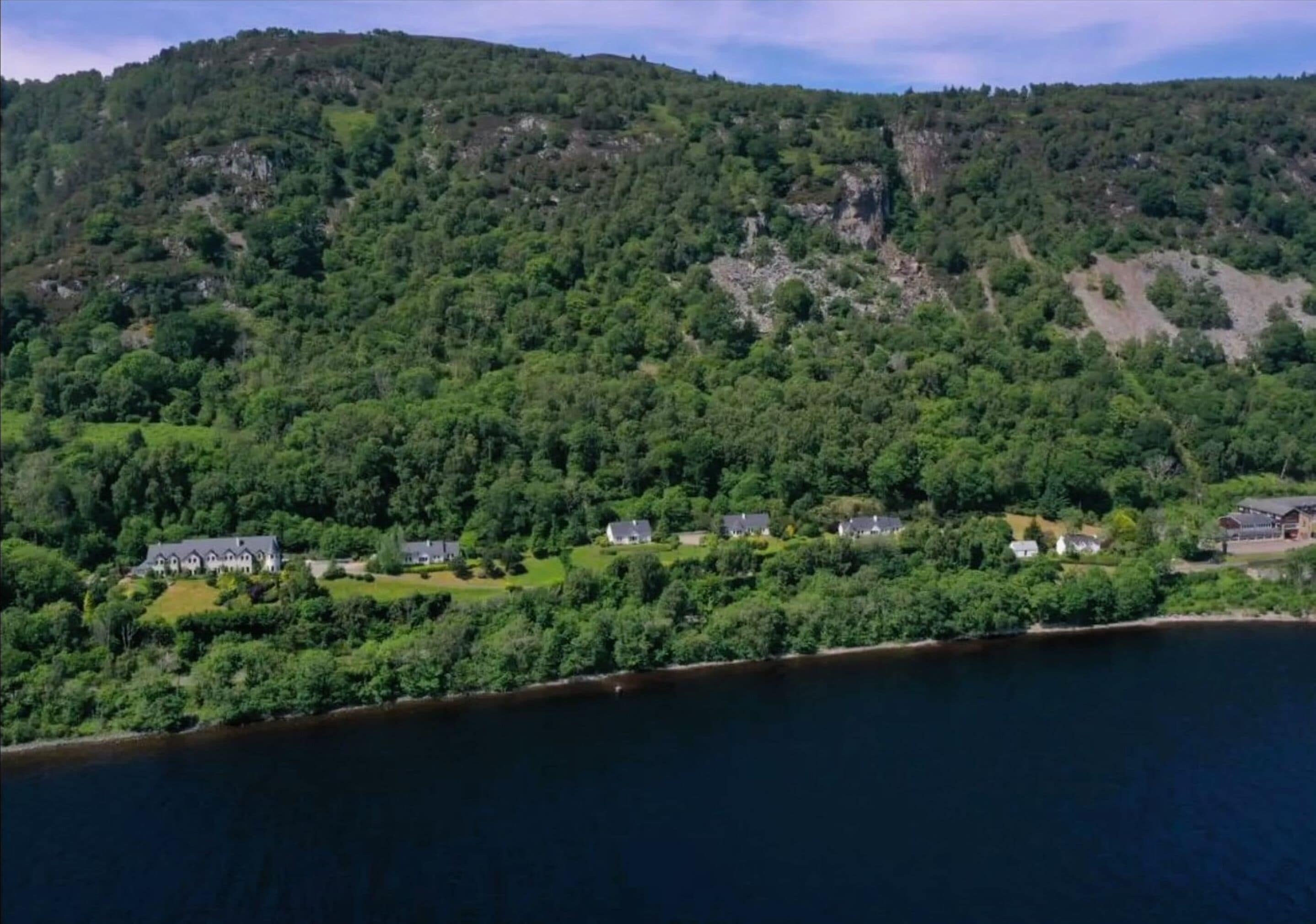 Une propriété située sur la côte, comprenant plusieurs maisons, entourée d’une forêt dense et bordée d’un lac.