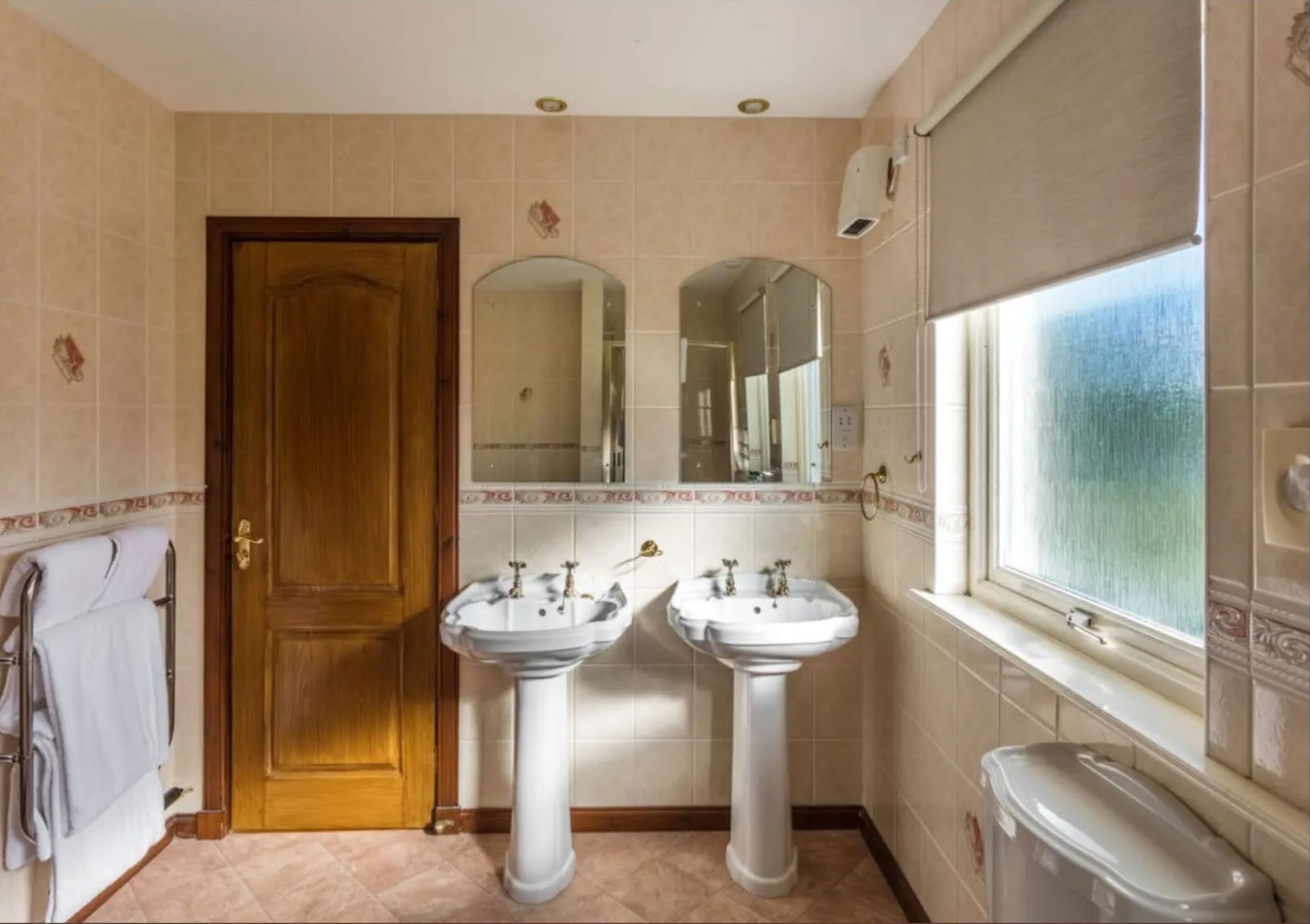 A bathroom with two sinks, a mirror, a towel rack, and a window.