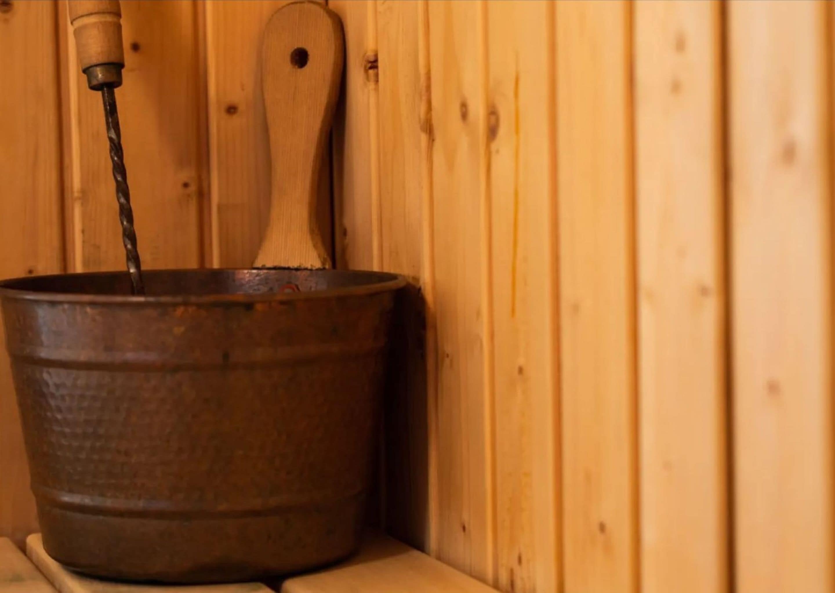 A rustic wooden cabin interior with a metal bucket and a wooden spoon.
