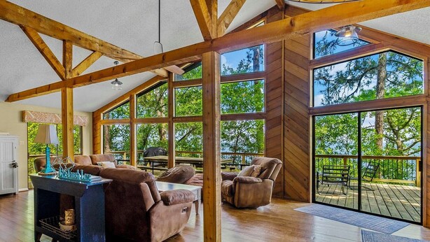 A spacious room with large windows, wooden beams, and a cozy seating area. - Lakefront “Treehouse”: Private Retreat in the Pines! (Point Blank)
