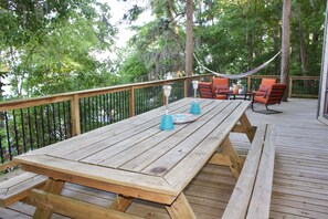 A wooden deck with a picnic table, orange chairs, and a hammock. - Lakefront “Treehouse”: Private Retreat in the Pines! (Point Blank)