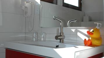 Un baño moderno con un tocador rojo, un lavabo blanco y un patito de goma amarillo.