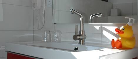 A modern bathroom with a red vanity, a white sink, and a yellow rubber duck.