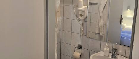 A bathroom with a toilet, sink, and mirror.