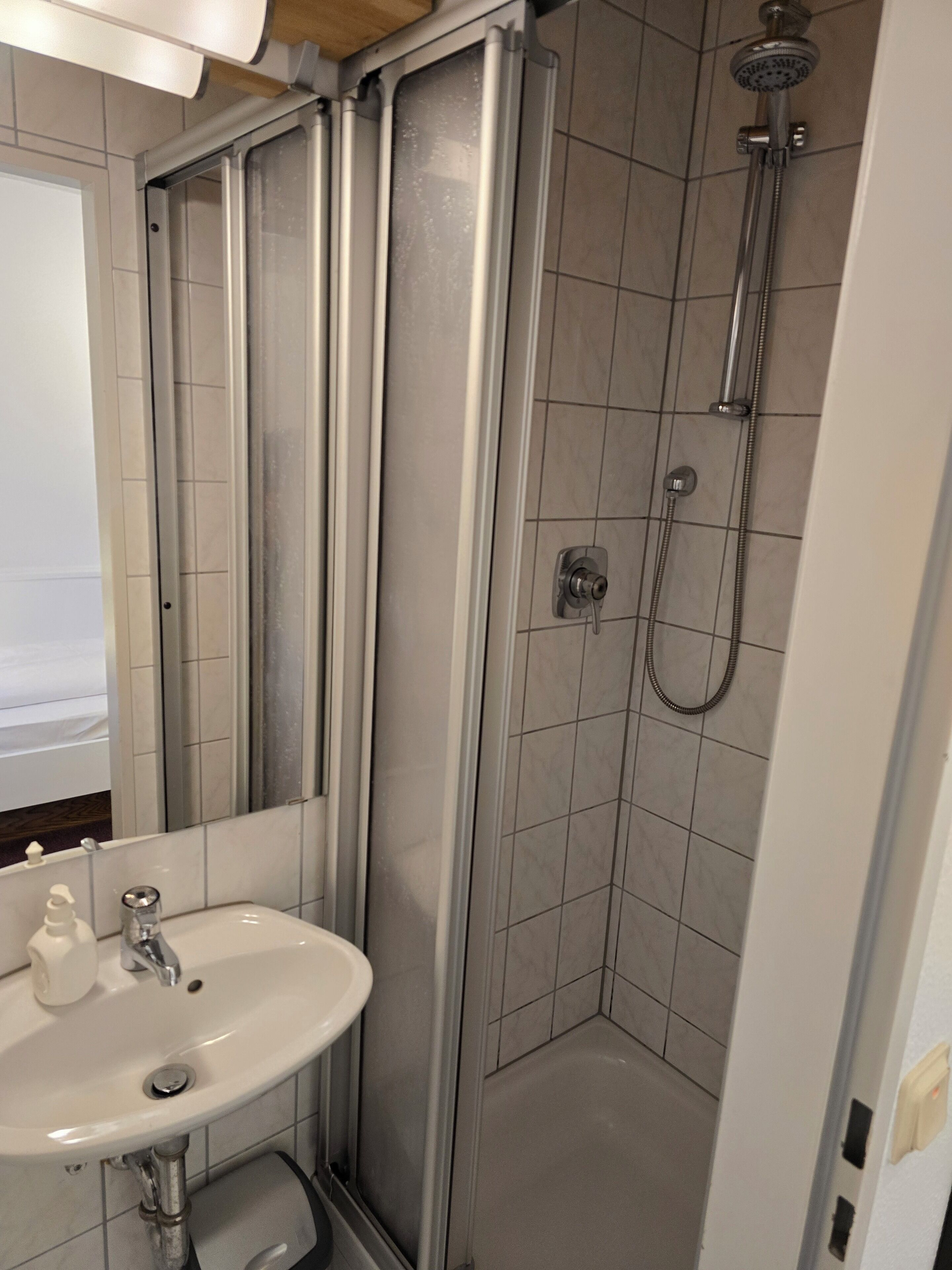 A modern bathroom with a shower, a sink, and a mirror.